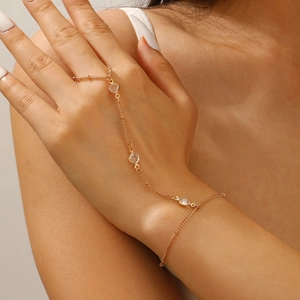 Close-up of golden hand chain with heart pendant and pearls worn on a model's hand