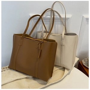 Close-up of minimalist brown and cream leather tote bags showcasing soft texture and shape