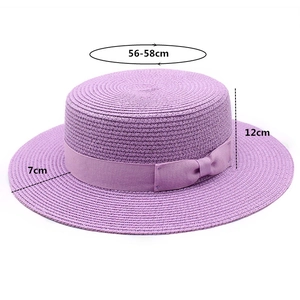 Detail of purple boater straw hat featuring a matching ribbon bow and fine weave texture