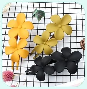 Flat lay of retro dual-flower matte hair clips in yellow and black on a mesh grid