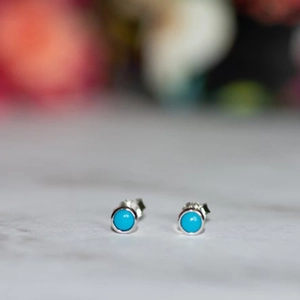Macro shot of 925 silver stud earrings featuring round turquoise stones and floral details