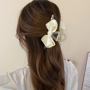 Detail of cream satin ribbon bow hair claw clip with rhinestones worn on hair