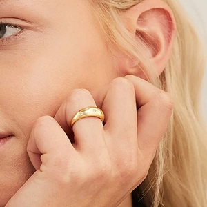 Golden dome ring with star engravings and cubic zirconia worn on a model's finger