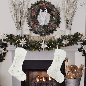 White plush Christmas stockings with gold and silver snowflake embroidery by a cozy fireplace