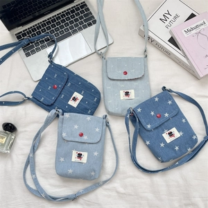 Gedetailleerde weergave van denim crossbodytassen met sterpatroon en schattige kattenpatch