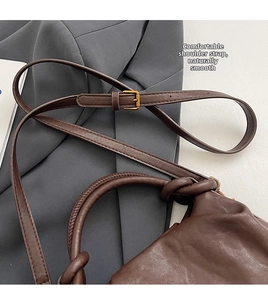 Dettaglio borsa in pelle marrone scuro con texture rustica e fibbia in bronzo