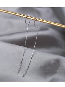 Detailed view of silver box chain tassel earrings hanging on a metal gold rod