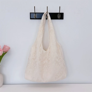 Detail of white lace tote bag hanging on a hook with pink tulips on a clean white wall