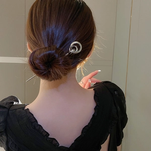 Silver layered hoop hair pin styled in a bun on a woman wearing a black dress