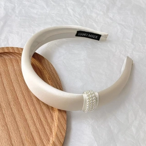 Detailed macro of a handmade cream silk headband with decorative faux pearls