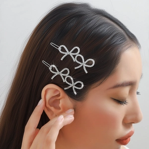 Set of two silver bow hair clips with rhinestones worn by a model in a minimalist style