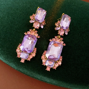 Detail view of vintage square earrings with purple and pink crystals on green velvet