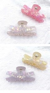 Detail view of 9cm acrylic hair claws in four pearlescent colors on a soft fabric