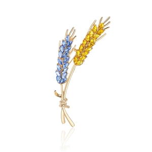 Elegant gold wheat ear brooch with blue and yellow crystals on a white background