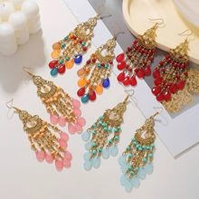 Detail of bohemian long tassel earrings with golden metal and colorful teardrop beads