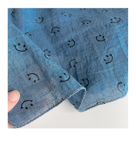 Close-up of lightweight blue triangular scarf showing soft texture and smiley face pattern