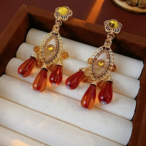 Detail of vintage gold earrings with rhinestones and amber teardrop beads on velvet