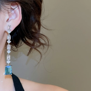 Close-up of model wearing 18K gold plated drop earrings with blue square zircon crystals
