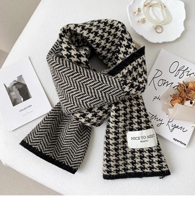 Detail of knitted houndstooth and herringbone scarf with elegant accessories and pearls