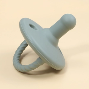 Detail view of a soft grey-blue silicone baby pacifier with textured handle and matte finish