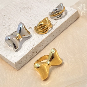 Two-tone gold and silver bow ring in polished stainless steel on a stone pedestal