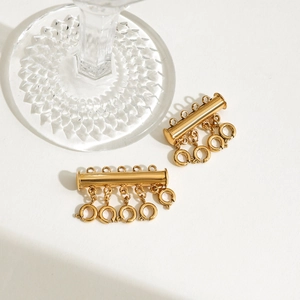 Macro detail of 18k gold stainless steel layered necklace clasps on glass base