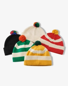 Flat lay of colorful striped knit beanies with fuzzy pom-poms for winter warmth