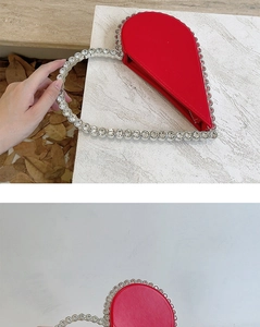 Macro view of red heart clutch bag featuring sparkling rhinestone handle for evening parties