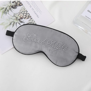 Detail view of grey silk sleep mask with Good Night embroidery and adjustable strap