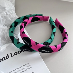 Detail view of woven headband featuring contrast color ribbon and white CHANGE lettering