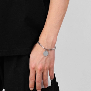 Détail du bracelet double chaîne argentée avec médaillon rond sur le poignet