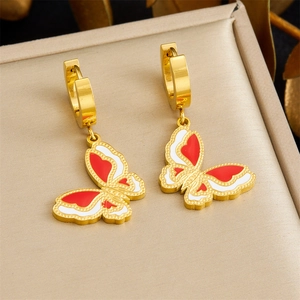 Detail of gold hoop earrings with red and white butterfly enamel pendants on jewelry box