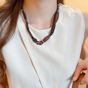 Detailed view of dark brown paisley silk scarf necklace with elegant wooden beads