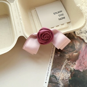 Detail of handmade pink and rose floral bow hair clip inside a vintage paper box