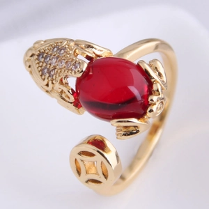 Macro shot of gold frog ring with red zircon and copper coin detail