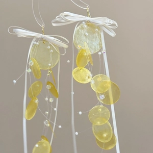 Elegant shell tassel earrings with white ribbon bows and yellow circular shell fragments
