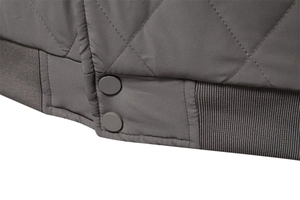 Detail of diamond quilted dark grey jacket with ribbed hem and matte press buttons