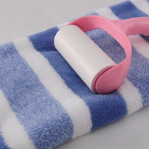 Rullo levapelucchi rosa che rimuove i peli da un asciugamano spesso a strisce blu