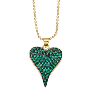 Détail du pendentif cœur doré avec zircons verts pavés sur une chaîne à billes dorée
