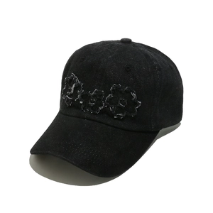 Detail of floral embroidery and distressed raw edges on black denim baseball cap