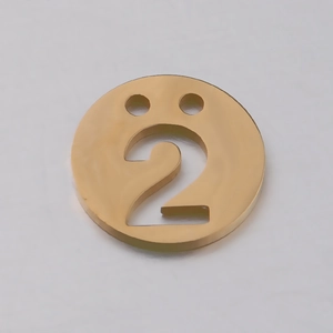 Macro d'un pendentif rond doré poli miroir avec motif évidé du chiffre 2 pour bijoux DIY