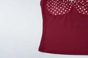 Detailed close-up of dark red fabric with white polka dots and fine stitching craftsmanship