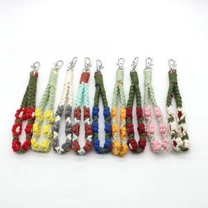 Flat lay of colorful handmade woven cotton flower wristlet keychains with metal clasps