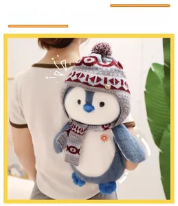 Detail of penguin plush toy with winter scarf and hat worn by a model in soft lighting