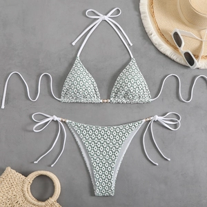 Detailed flat lay of white lace bikini set with gold rings and pearl accents