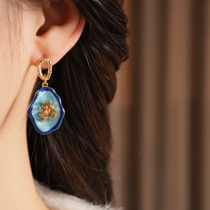 Close-up of vintage oval flower earring with blue enamel and gold coral detail