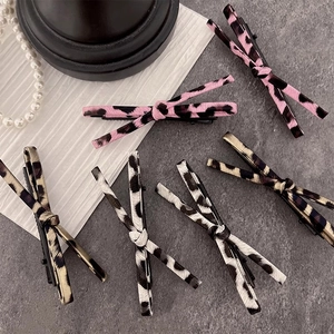 Set of six stylish leopard print bow hair clips in various colors on a stone background