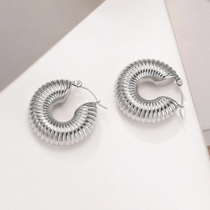 Detailed macro view of silver croissant style hoop earrings with thick threaded texture