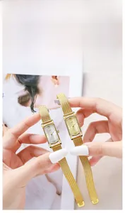 Detailed macro view of a vintage gold rectangular watch with a Milanese mesh strap