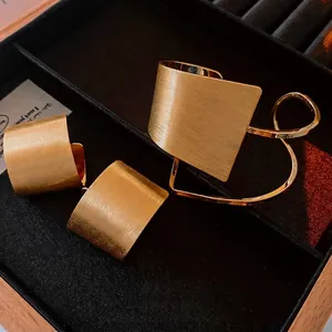 Elegant gold plated brushed metal jewelry set including rectangular earrings and bracelet